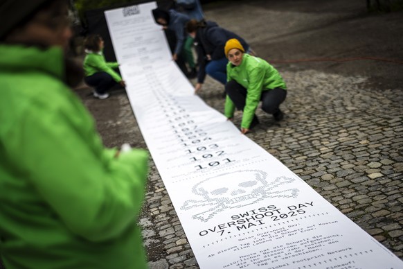 Aktivisten von Greenpeace und Studierende der Zuercher Hochschule der Kuenste (ZHdK) praesentieren eine uebergrosse 70 Meter lange Quittung beim Zuercher Lindenhof, am Dienstag 6. Mai 2025 in Zuerich. ...