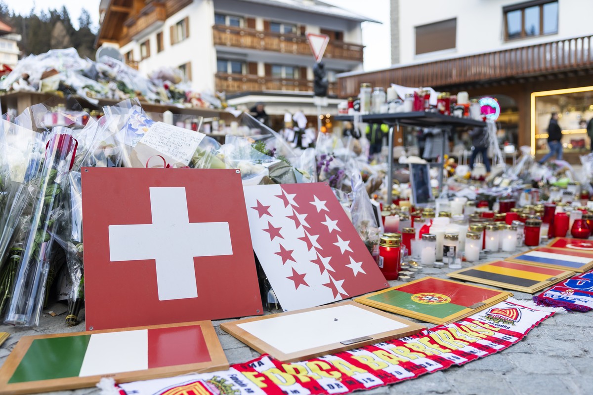 Plaques bearing flags representing Switzerland, Romania, Italy, Portugal, Belgium, France, and Turkey were placed along with flowers and candles in tribute to the victims after the fire at the "L ...