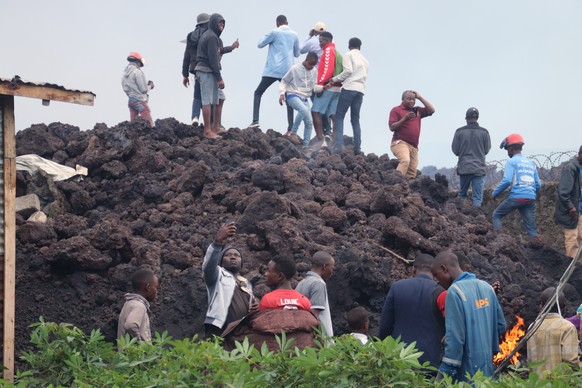 People gather on a stream of cold lava rock following the overnight eruption of Mount Nyiragongo in Goma, Congo, Sunday, May 23, 2021. Witnesses say Congo���s Mount Nyiragongo volcano unleashed lava t ...