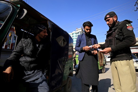 epa10408912 A Pakistani security official checks people at a roadside checkpoint as security in the provincial capital of KPK province has been intensified following attacks on a police station that k ...
