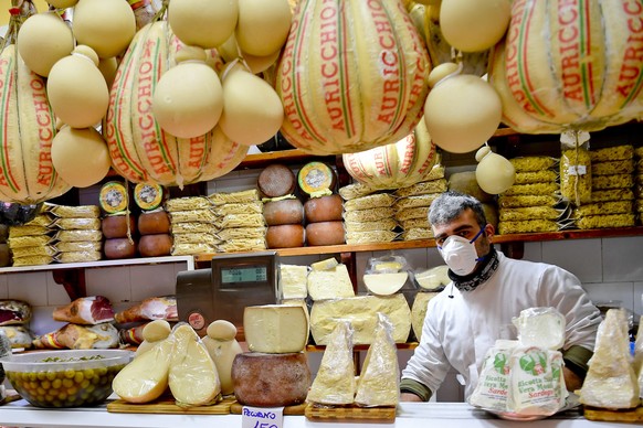 epa08300223 A worker, wearing a medical mask and gloves, waits for customers in the local markets that remain open in Naples, Italy, 17 March 2020. Italy now has more than 27,000 covid-19 cases, 2,158 ...