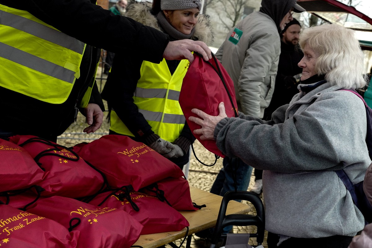 epa10375778 A woman receives a Christmas gift at a humanitarian aid distribution point at Berlin's Schoeneberg district, Germany, 21 December 2022. A Caritas food truck organized by German musici ...