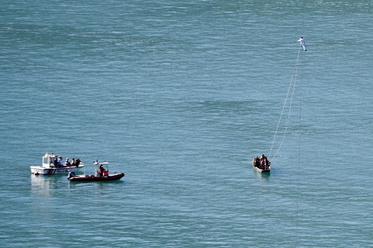 Swiss tightrope artist Freddy Nock, sitting on a rope, gets ready to lower himself onto a dinghy as he aborts his second attempt to cross the Thunersee, the lake of Thun, on a rope, near Sundlauenen i ...