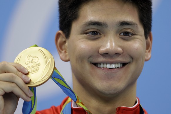 Singapore's Joseph Schooling shows off his gold medal in the men's 100-meter butterfly medals ceremony during the swimming competitions at the 2016 Summer Olympics, Friday, Aug. 12, 2016, in Rio de Janeiro, Brazil. (AP Photo/Michael Sohn)