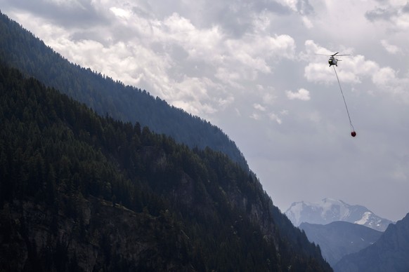 epa10753317 A helicopter takes part in efforts to extinguish forest fires above the communes of Bitsch and Ried-Moerel, in Moerel-Filet, Switzerland, 18 July 2023. A forest fire broke out above Bitsch ...