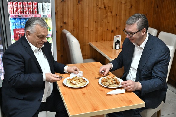 epa12552529 A handout photo made available by the Serbian Presidency shows Serbian President Aleksandar Vucic (R) and Hungarian Prime Minister Viktor Orban (L) having burek (leafy cheese or meat pie)  ...
