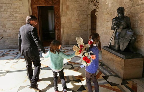 Carles Puigdemont und seine Töchter Magali und Maria im Palast der katalanischen Regionalregierung in Barcelona. Am Tag der Frau im Jahr 2016 erhielten sie Blumen. Die kniende Statue steht für den kat ...