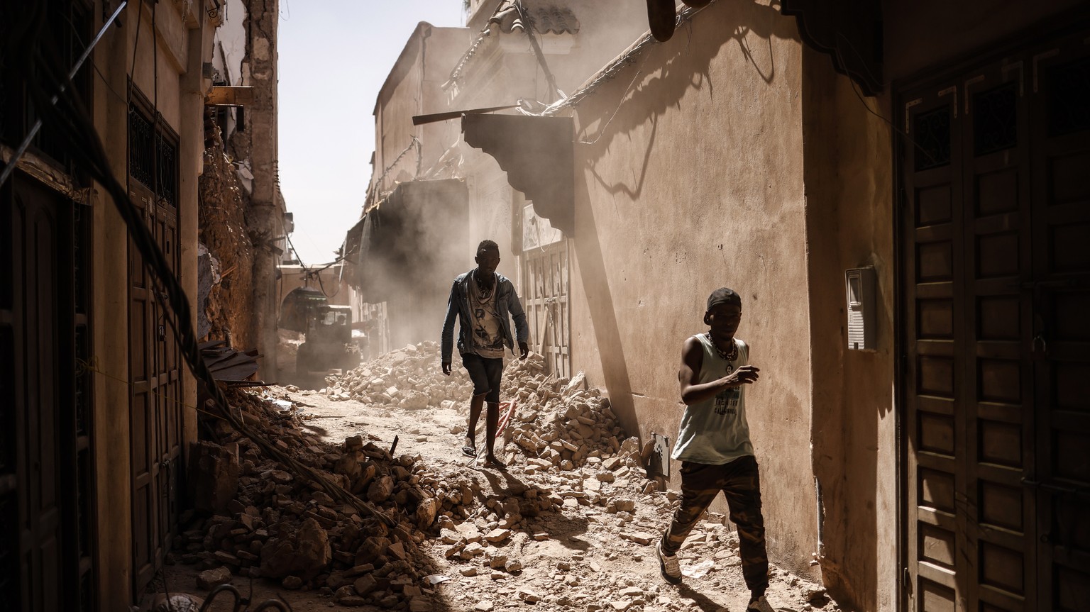 epaselect epa10854426 People walk over the rubble of a damaged building inside the Medina following a powerful earthquake in Marrakesh, Morocco, 11 September 2023. A magnitude 6.8 earthquake that stru ...