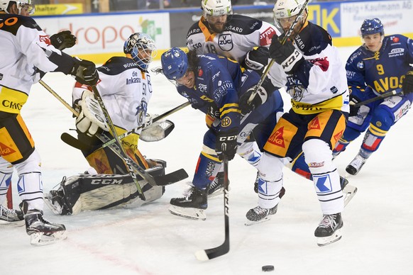 Zugs Torhueter Tobias Stephan beobachtet Davos Dino Wieser, Zugs Dominik Schlumpf und Josh Holden, von links, beim Eishockey-Qualifikationsspiel der National League A zwischen dem HC Davos und dem EV  ...