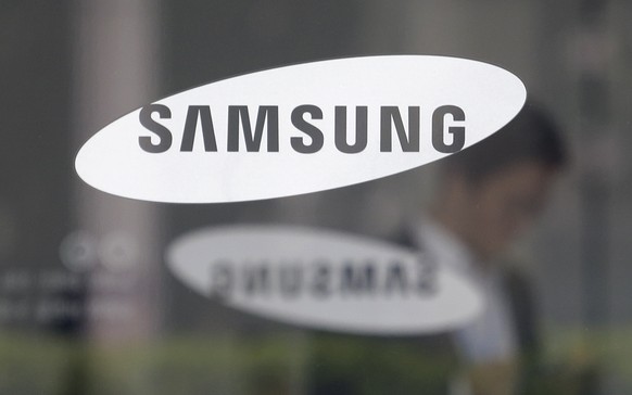 FILE - In this April 30, 2019, file photo, an employee walks past a logo of the Samsung Electronics Co. at its office in Seoul, South Korea. A day ahead of his release on parole, billionaire Samsung s ...