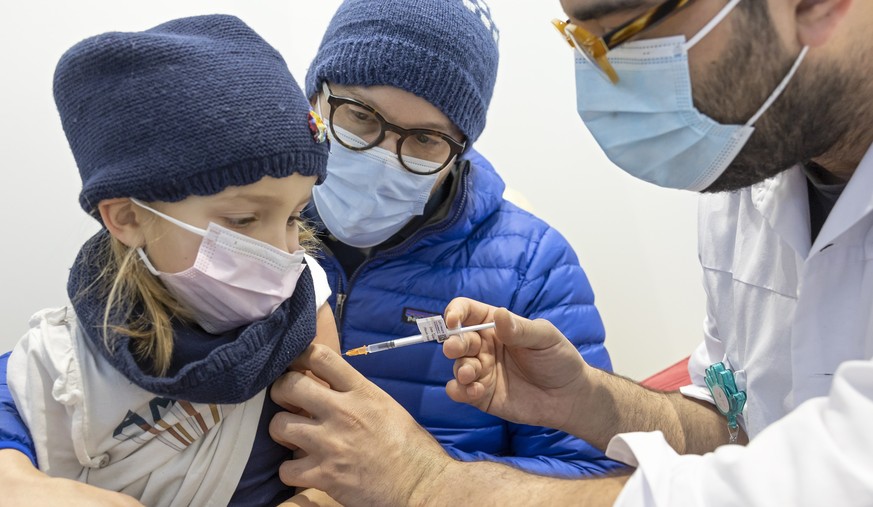 epa09667812 Alexandra (L), 5 year-old, receives a dose of the COVID-19 Pfizer vaccine at the vaccination center of the Geneva University Hospitals (HUG), in Geneva, Switzerland, 05 January 2022. Frenc ...