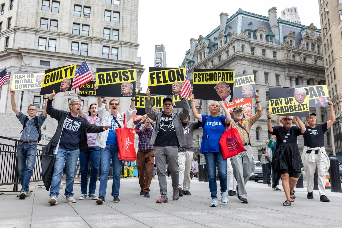 Des manifestants protestant contre Donald Trump arborent des pancarte renvoyant aux accusations et condamnation qui visent le président américain.