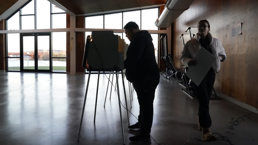 A voter walks to cast their ballot as another fills his out at the Eleanor Boathouse polling place on the Southside of Chicago, Tuesday, Nov. 8, 2022. (AP Photo/Charles Rex Arbogast)