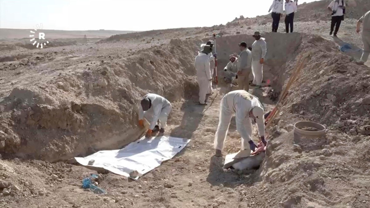 In this image taken from video provided by Rudaw TV, workers dig out human remains at the Khasfa site near the northern Iraqi city of Mosul, where authorities have begun excavating a mass grave believ ...