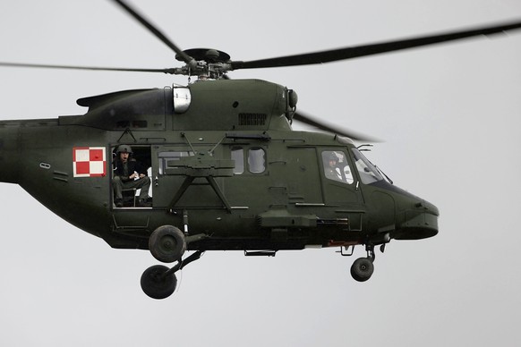 A Polish military helicopter fly over a group of migrants from the Middle East and elsewhere gathering at the Belarus-Poland border near Grodno, Belarus, Monday, Nov. 8, 2021. Poland increased securit ...