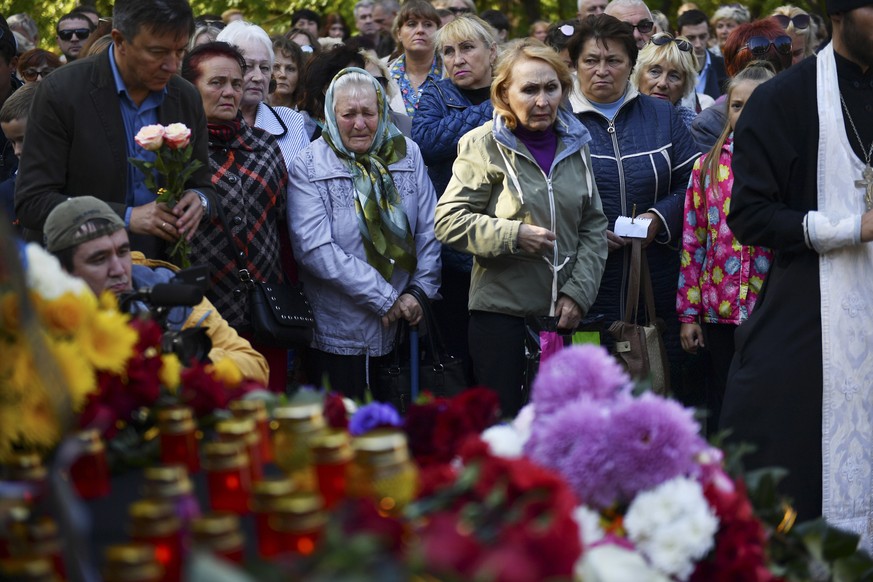 People place flowers by a national memorial during a ceremony commemorating an attack on a vocational college, in Kerch, Crimea, Thursday, Oct. 18, 2018. An official says that authorities on the Crime ...