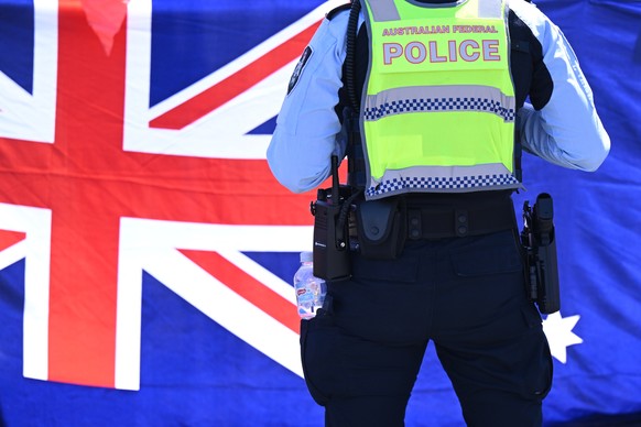 epa12545097 A police officer stands in front of an Australian flag ahead of the arrival of Zhao Leji, Chairman of the Standing Committee of the National Peoples Congress, Peoples Republic of China a ...
