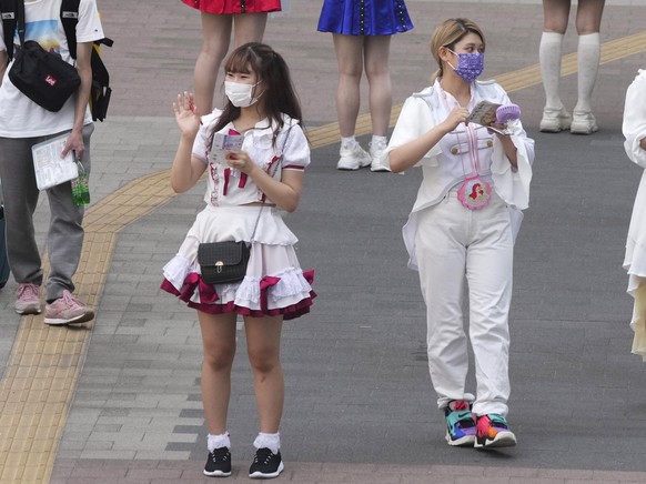 epa09358069 A view of women wearing costumes and protective face masks at Akihabara in Tokyo, Japan, 22 July 2021. The Tokyo Metropolitan Government announced on the day 1,979 new COVID-19 cases. The  ...