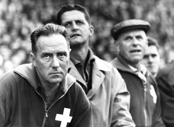 Alfredo Foni (1911-1985), links, Coach der Schweizer Fussballnationalmannschaft, beobachtet ein Spiel am 11. November 1964 mit ernster Miene. Neben ihm Roger Quinche und Pfleger Hari. Foni trainierte  ...