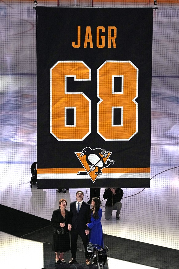 Former Pittsburgh Penguins player Jaromir Jagr, bottom center, along with his mother, left, and girlfriend watch as his uniform number is raised to the rafters of PPG Paints arena after being retired  ...