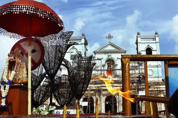 epa07548207 Sri Lankan Christian’s lighting candles on temporary stand opposite St Anthony’s church damage by suicide attack while navel personnel engage in reconstruction work in Colombo, Sri Lanka 0 ...