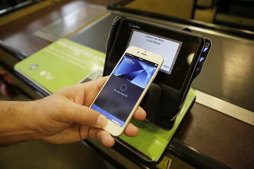 FILE - In this photo taken Friday, Oct. 17, 2014, Eddy Cue, Apple Senior Vice President of Internet Software and Services, demonstrates the new Apple Pay mobile payment system at a Whole Foods store i ...