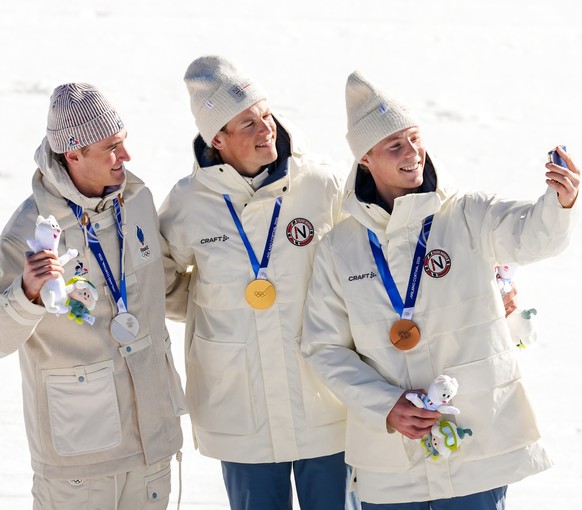 Silver medalist Mathis Desloges, of France, from left, gold medalist Johannes Hoesflot Klaebo, of Norway, and bronze medalist Einar Hedegart, of Norway, pose for a selfie after the cross country skiin ...
