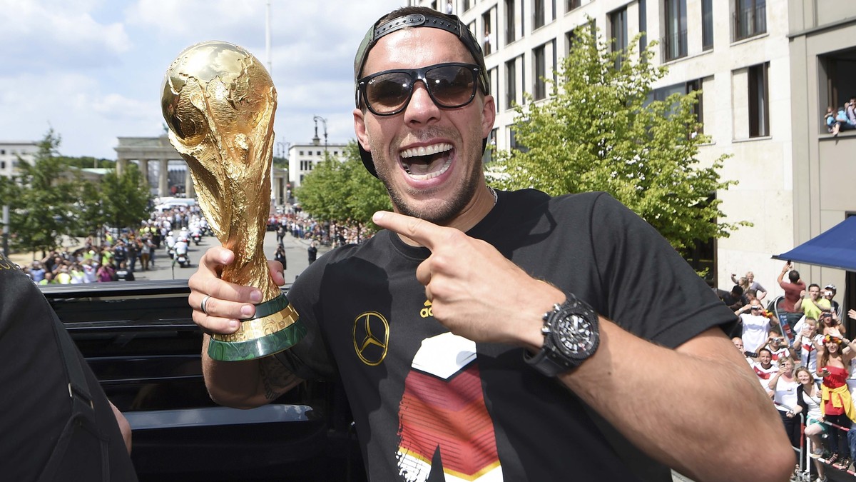 Germany's Lukas Podolski poses with the World Cup trophy during celebrations to mark the team's 2014 Brazil World Cup victory in Berlin July 15, 2014. Germany's victorious soccer team l ...