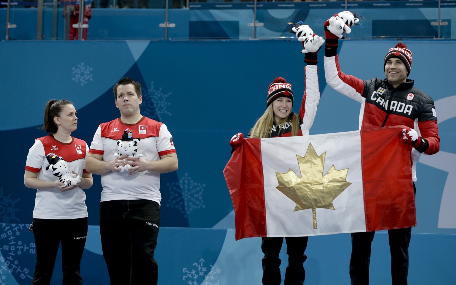 Canada&#039;s Kaitlyn Lawes, second right, and John Morrison, right, celebrate holding their flag after winning gold, as second place curlers Switzerland Jenny Perret, left, and Martin Rios look on at ...