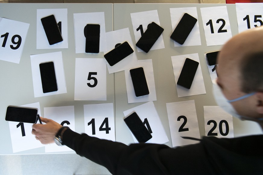 EPFL staff member wearing protective face mask preparing smart phones for a test of a app using Decentralized Privacy-Preserving Proximity Tracing (DP-3T) at the Swiss Federal Institute of Technology  ...