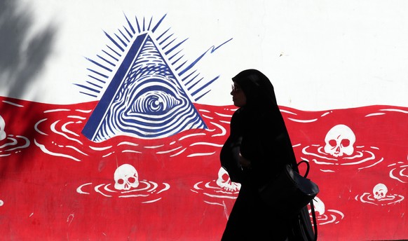 epaselect epa10160875 A silhouetted Iranian woman walks past an anti-US wall painting on the wall of former US embassy in the capital city of Tehran, Iran, 05 September 2022. Following the indirect ex ...