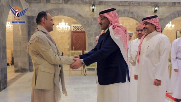 In this handout photo released on April 9, 2023 by the media arm of the Houthi group, Ansar Allah, the Houthi's Supreme Political Council, Mahdi al-Mashat, left, shakes hands with the Amba of Saudi Arabia...