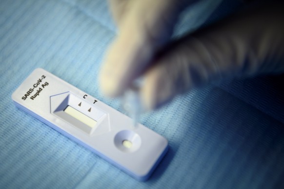 epa08809321 A health worker performs a SARS-CoV-2 Rapid Antigen Test from the Swiss multinational healthcare company Roche just after collecting a nose swab sample for a polymerase chain reaction (PCR ...