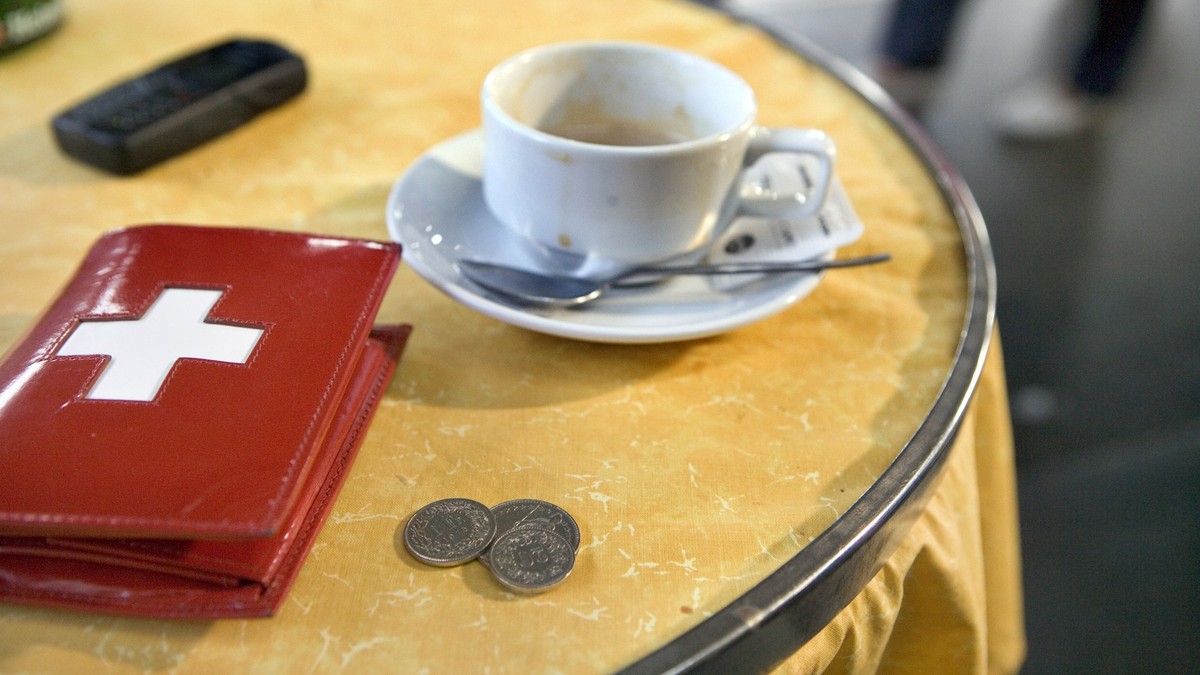 Ein Portemonnaie mit einem Schweizer Kreuz, eine Kaffeetasse, ein Handy und ein paar Muenzen in einem Restaurant im Hauptbahnhof Zuerich, aufgenommen am 24. Oktober 2005. (KEYSTONE/Martin Ruetschi)

A ...