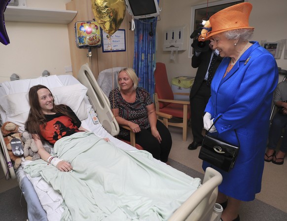 Britain&#039;s Queen Elizabeth II. right, speaks to Millie Robson, 15, and her mother, Marie, as she visits the Royal Manchester Children&#039;s Hospital in Manchester England, to meet victims of the  ...