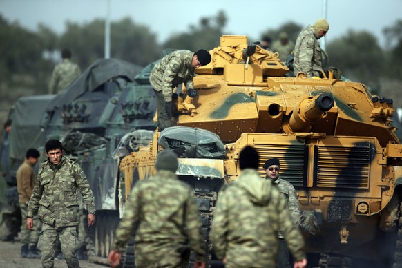 Turkish Army soldiers prepare their tanks at a staging area in the outskirts of the village of Sugedigi, Turkey, on the border with Syria, Monday, Jan. 22, 2018. The Turkish offensive on the Kurdish e ...