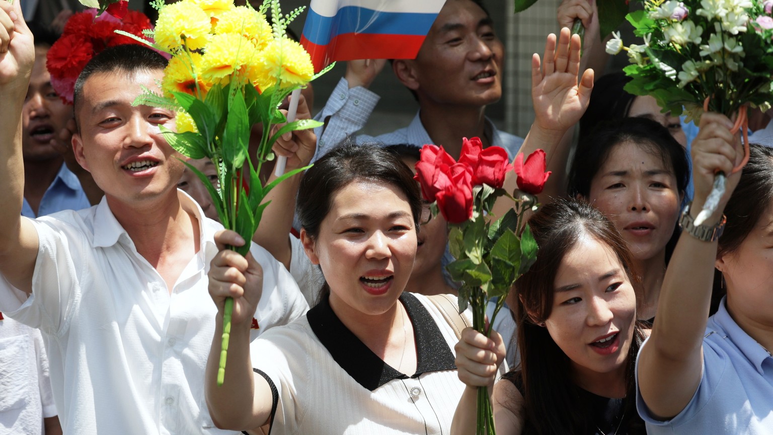 epa11421555 North Korean people line up on the street side and welcome the motorcade of Russian President Vladimir Putin and North Korean leader Kim Jong Un during their meeting in Pyongyang, North Ko ...