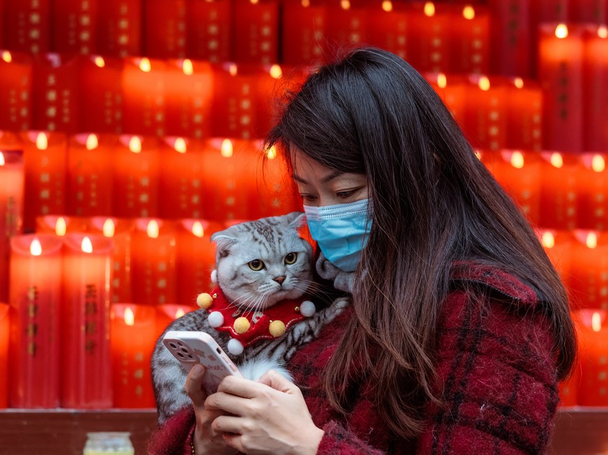 epaselect epa10422474 A woman carrying a cat walks on the first day of the Chinese Lunar New Year in the Jade Buddha Temple, in Shanghai, China, 22 January 2023. Chinese New Year, also known as the Sp ...