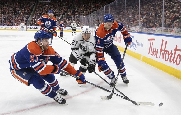 Los Angeles Kings&#039; Trevor Moore (12) battles for the puck with Edmonton Oilers&#039; Connor McDavid (97) and Evan Bouchard (2) during the third period of NHL hockey game in Edmonton, Alberta, on  ...
