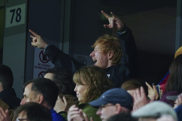 Ipswich Town fan Ed Sheeran, top, cheers for his team during the English Premier League soccer match between Ipswich Town and Manchester United at Portman Road stadium in Ipswich, England, Sunday, Nov ...