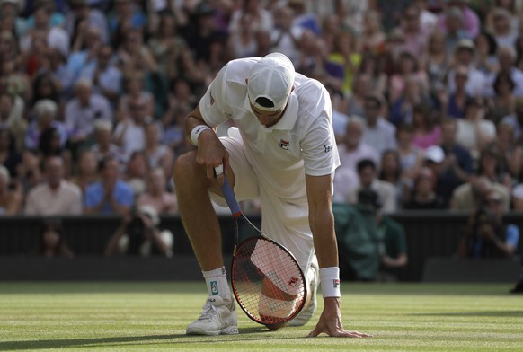 John Isner of the United States kneels after stumbling as he returned the ball to South Africa&#039;s Kevin Anderson during their men&#039;s singles semifinals match at the Wimbledon Tennis Championsh ...