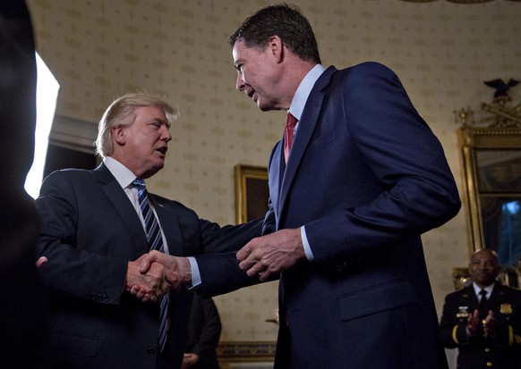 epa05742575 US President Donald J. Trump, center, shakes hands with James Comey, director of the Federal Bureau of Investigation (FBI), during an Inaugural Law Enforcement Officers and First Responder ...