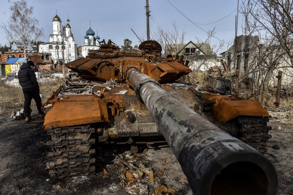 epa10488278 A man walks past a wrecked Russian tank in Sviatohirsk, Donetsk region, Eastern Ukraine, February 24, 2023. Russian troops entered Ukrainian territory on February 24, 2022, starting a conf...
