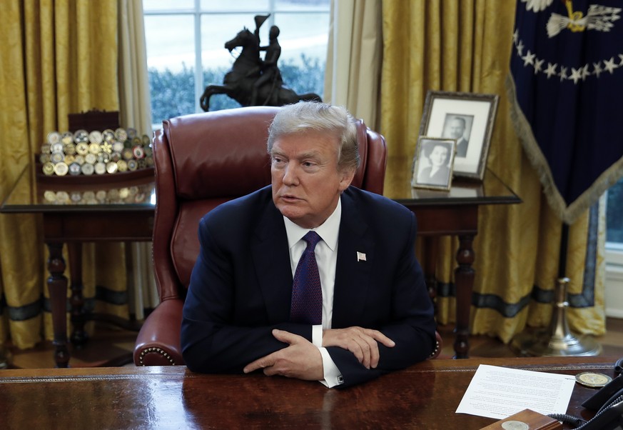 President Donald Trump sits at the Resolute Desk after signing Section 201 actions in the Oval Office of the White House in Washington, Tuesday, Jan. 23, 2018. Trump says he is imposing new tariffs to ...