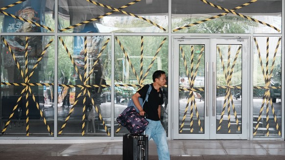 A passenger walks by a closed door of a coach station where all glass windows and doors are reinforced with protective tape in preparation for the approaching Typhoon Dolphin in Hangzhou in eastern Ch ...