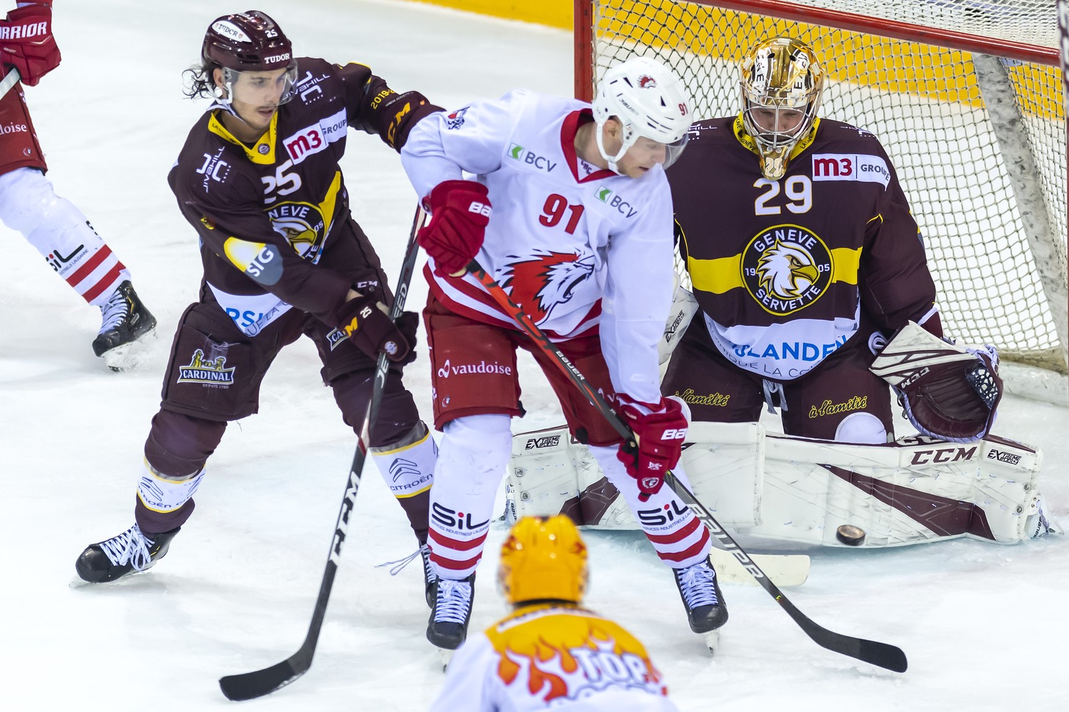 Le joueur du club lausannois, Joel Vermin, centre, a la lutte pour le puck avec le joueur du club genevois, Roger Karrer, gauche, devant le gardien genevois, Robert Mayer, droite, lors du match du cha ...