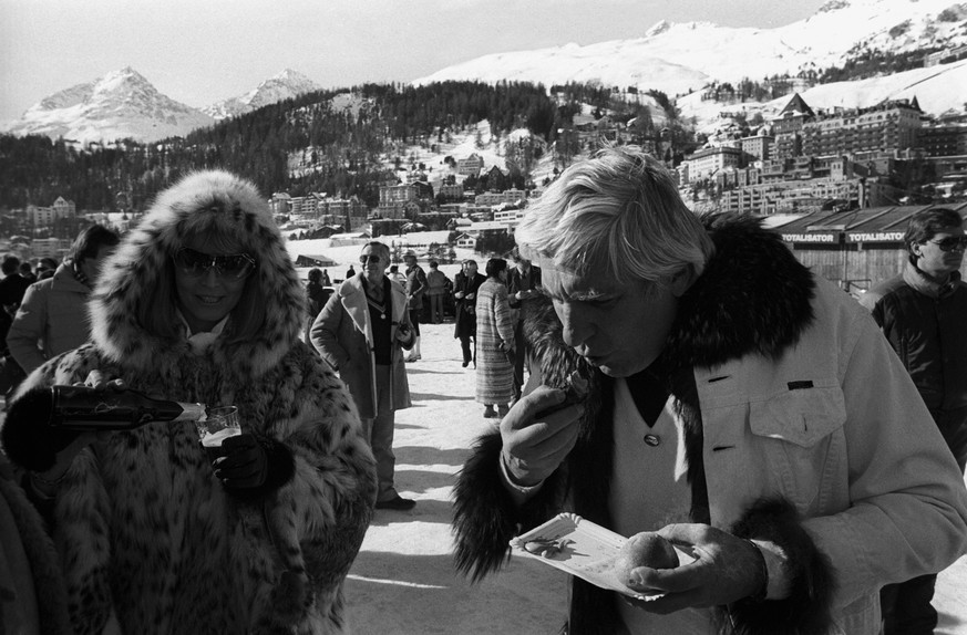 Reich, aber bodenständig:&nbsp;Gunter Sachs isst 1985 während des Sotheby's Cup auf dem gefrorenen St.Moritzersee eine Wurst, während seine Frau Mirja ein Bier geniesst.