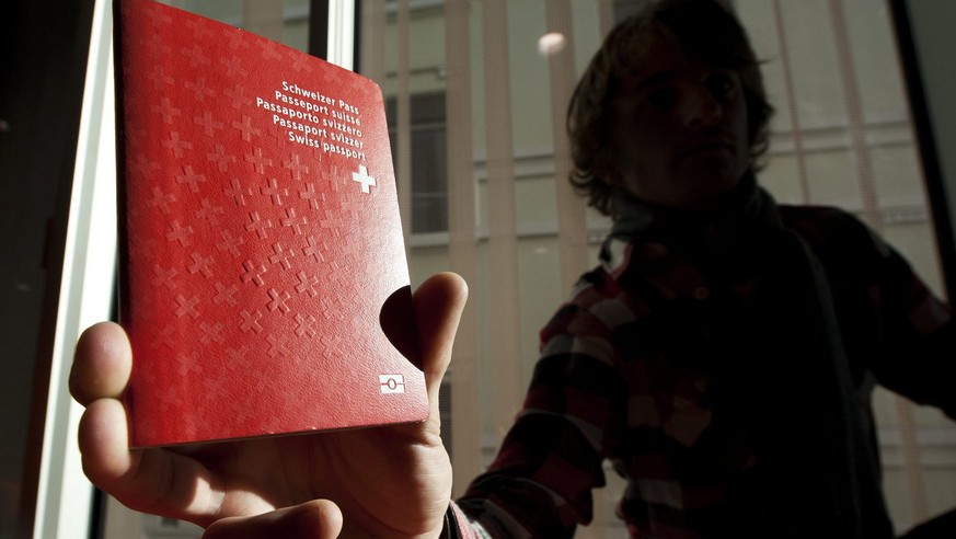 Un homme tient un passeport biometrique Suisse dans le nouveau centre de biometrie au Flon ce vendredi 21 janvier 2011 a Lausanne. Ce centre va recolter les donnees biometriques pour les passeports su ...