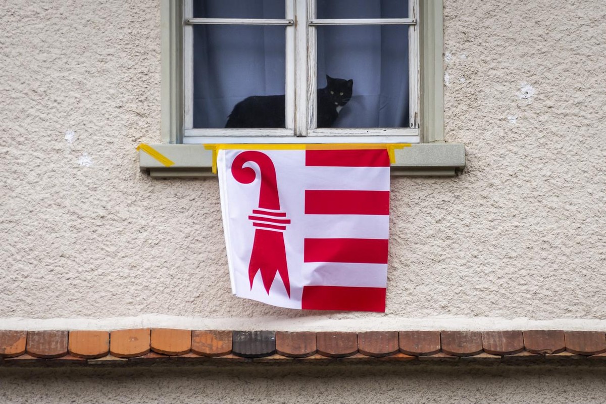 Un chat noir passe devant un drapeau du canton du Jura accroche a une fenetre d'une maison le jeudi 4 mars 2021 a Moutier. Le 28 mars prochain, les Prevotois doivent revoter sur l'appartenan ...