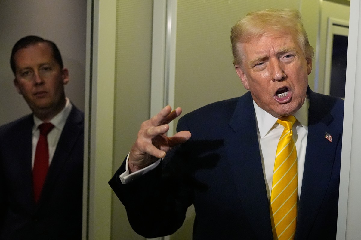 President Donald Trump speaks to reporters on Air Force One on his way to his Mar-a-Lago estate in Palm Beach, Fla., Friday, Nov. 14, 2025, as U.S. Ambassador to India Sergio Gor listens. (AP Photo/Ma ...